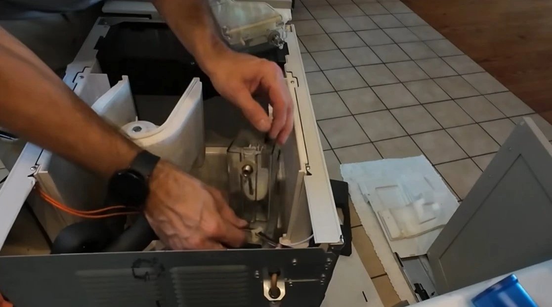 Technician's hands repairing an internal appliance component