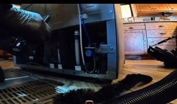 Technician servicing the back panel of a refrigerator