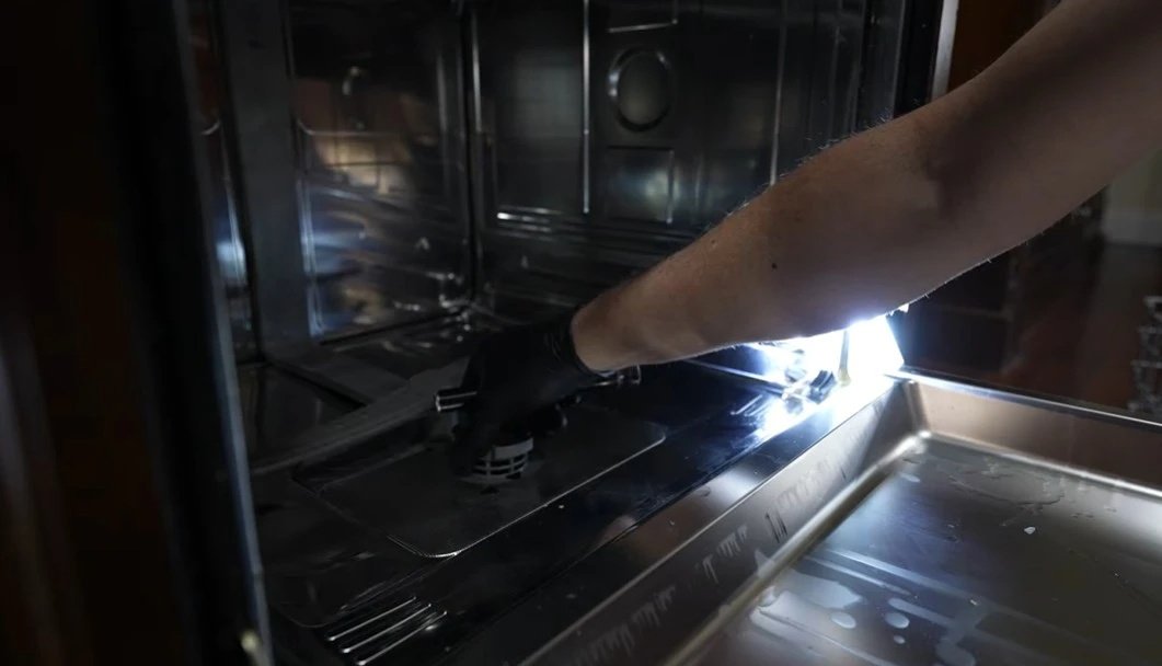 Technician's hands adjusting an internal washing machine component during repair